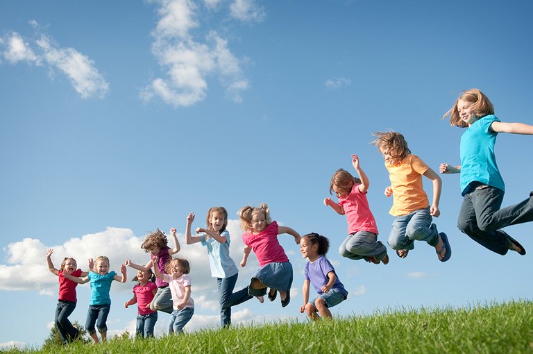 Springende Kinder auf einer grünen Wiese